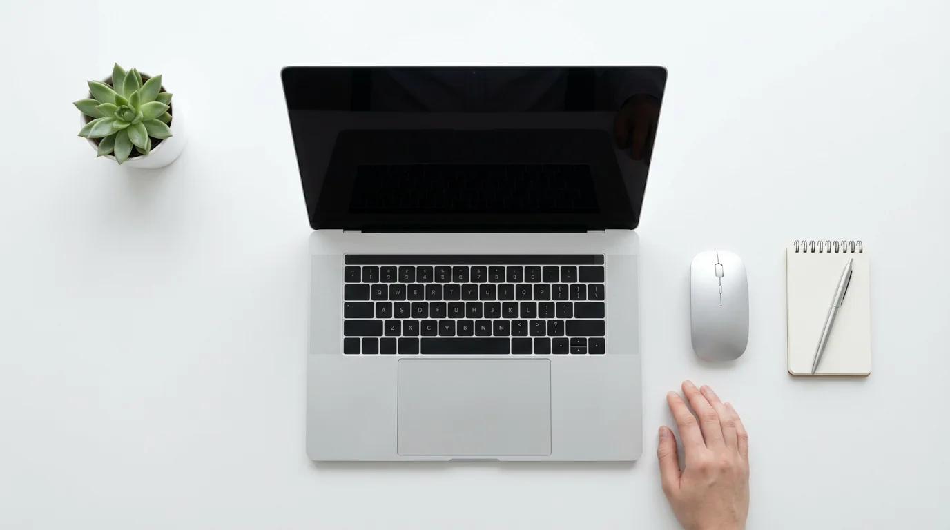 Overhead view of a tidy white desk with a laptop, mouse, and organized office supplies.