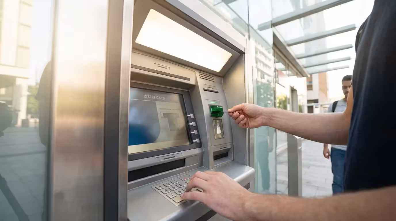 A person using an ATM, demonstrating the two-step process of card and PIN.