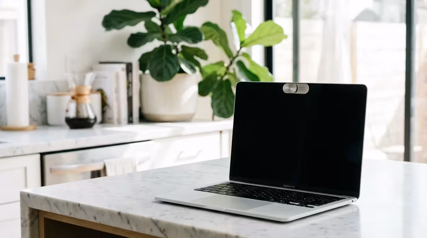 Detailed shot of a laptop with a privacy cover over the webcam on a clean counter.